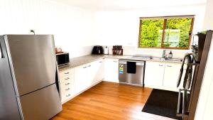 a kitchen with white cabinets and a stainless steel refrigerator at Blue Bay Escape in Venus Bay +8 photos