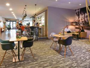a restaurant with tables and chairs and people sitting at tables at ibis Kortrijk Centrum in Kortrijk