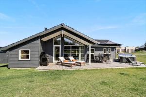 a black house with a deck with a grill and a grill at 30439-Odder-Strandvaenget-74 in Odder