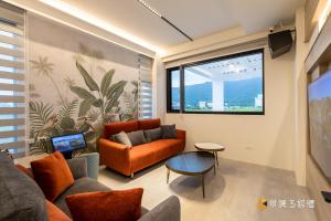 a living room with orange furniture and a large window at 亮Villa in Sanxing