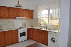 a kitchen with wooden cabinets and a sink and a window at Dream Villas in Lefkos Karpathou