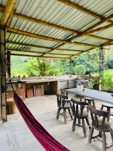 a hammock on a patio with a table and chairs at Finca Lantana Oficial in Villeta