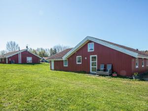 a red barn with two chairs in a yard at 4 star holiday home in Nordborg in Nordborg