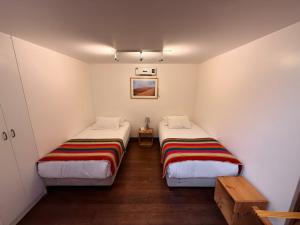 two beds in a room with white walls and wooden floors at Pampa Hotel Boutique in Iquique