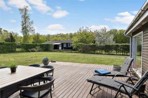 a patio with a table and chairs on a deck at 30463-Odder-Solbakken-14 in Odder +20 photos