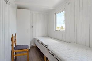 a white bedroom with a bed and a chair at 30463-Odder-Solbakken-14 in Odder