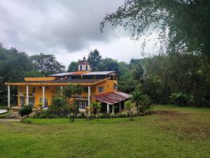 a large yellow house with a tower on top of it at EL Jardin De Los Anturios in Xico