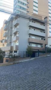 a large apartment building next to a brick street at Apartamento - 2 Quartos * Completo * Central in Bento Gonçalves