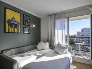 a hotel room with two beds and a balcony at Aparthotel Adagio Paris Buttes Chaumont in Paris