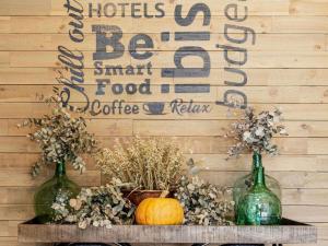 two green bottles on a table with pumpkins and a wall at Ibis Oviedo in Oviedo
