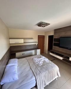 a bedroom with a bed and a flat screen tv at Pousada Recanto do Bosque in Luziânia