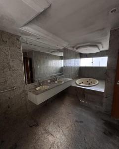 a bathroom with two sinks and two mirrors at Pousada Recanto do Bosque in Luziânia