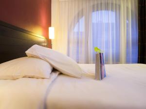 a bird perched on top of a bed with pillows at Ibis Styles Metz Centre Gare in Metz