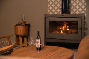 a bottle of wine and a glass on a table in front of a fireplace at Dobe Lodge in Vista Flores