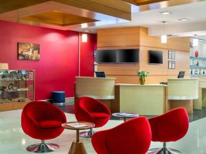 a waiting room with red chairs and a counter at Ibis Gaziantep in Gaziantep