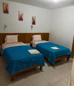 two beds in a room with blue sheets at hotel esmeralda in Chiclayo