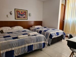a hotel room with two beds and a table at hotel esmeralda in Chiclayo