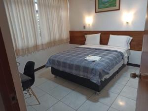 a hotel room with a bed and a chair at hotel esmeralda in Chiclayo
