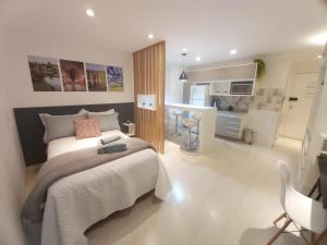 a bedroom with a large bed and a kitchen at Lindo studio equipado em apartamento clube com academia e conforto no centro de Curitiba - MID Home in Curitiba