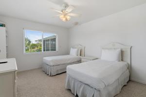a bedroom with two beds and a ceiling fan at Seaside Rendezvous in Sanibel +64 photos