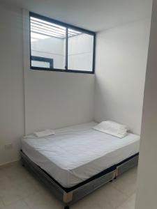 a bed in a white room with a window at Casa Sol & Descanso Tocaima in Tocaima