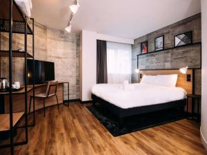 a bedroom with a bed and a desk and a television at ibis Belfast City Centre in Belfast