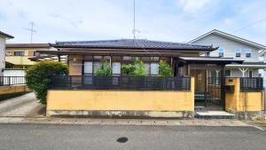 a yellow house with a black fence in front of it at 足利すまいるハウス in Ashikaga