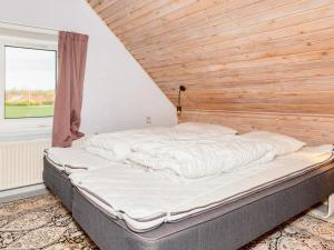 a large bed in a room with a wooden wall at Lush holiday home in Thyholm in Thyholm