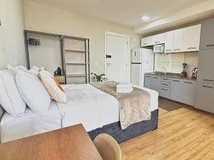 a bedroom with a large bed and a kitchen at Franklin Studio Prime Rio Energy - Piscina, Sauna, Academia in Rio de Janeiro