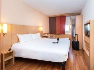 a hotel room with a large bed with a laptop on it at ibis Lyon Est Chaponnay in Chaponnay +76 photos
