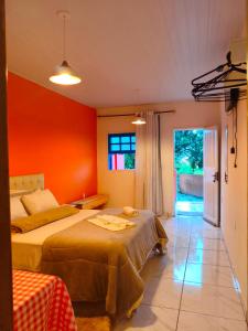 a bedroom with two beds and an orange wall at Pousada Alforria Lavras Novas centro in Lavras Novas