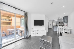 a living room with a tv and a kitchen at Central Alpine Condo in Whistler