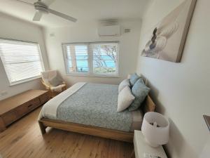 a bedroom with a bed and two windows at Esplanade Bliss in Cronulla
