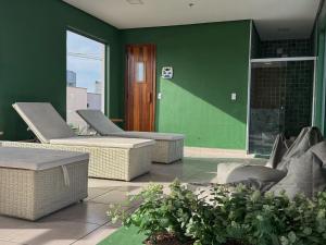 a patio with two chairs and a green wall at Franklin Studio Prime Rio Energy - Piscina, Sauna, Academia in Rio de Janeiro