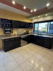 a kitchen with black cabinets and a large window at Beach house in San Miguel, Ensenada in Ensenada