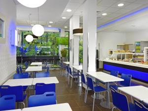 a restaurant with white tables and blue chairs at Ibis Budget Lleida in Lleida