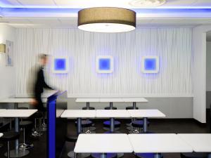 a man walking in a room with tables and chairs at Ibis Budget Lleida in Lleida +91 photos