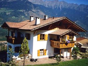 une maison blanche avec un balcon et des montagnes en arrière-plan. dans l'établissement Biohof Niedereben, à Rablà