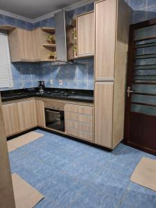 a kitchen with wooden cabinets and a blue tile floor at Casa c Piscina em Holambra in Holambra
