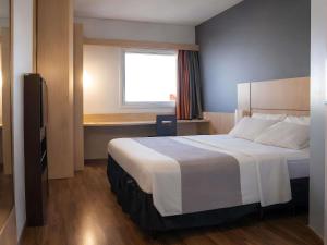 a hotel room with a large bed with a window at ibis Contagem Ceasa in Contagem +96 photos