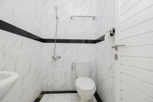 a white bathroom with a toilet and a sink at RedDoorz Plus near Politeknik Negeri Malang in Malang +14 photos