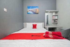 a bedroom with a large bed with red pillows on it at RedDoorz Plus near Politeknik Negeri Malang in Malang