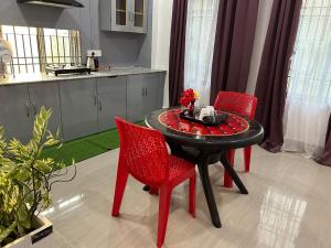 a kitchen with a table and two red chairs at Pearl Haven in Jorhat +3 photos