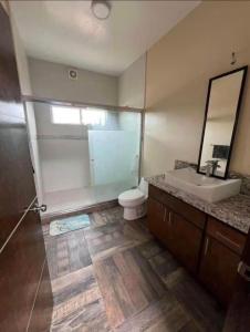 a bathroom with a toilet and a sink and a mirror at CasaLyz in Rosarito Beach