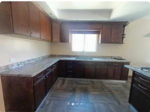 an empty kitchen with wooden cabinets and a window at CasaLyz in Rosarito Beach