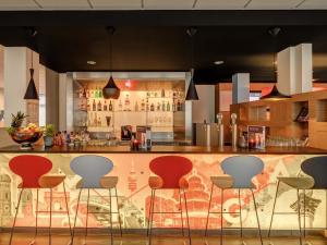 a bar with red chairs in a kitchen at ibis München City Süd in Munich