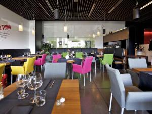 a restaurant with colorful chairs and tables in a restaurant at Mercure Nerocubo Rovereto in Rovereto