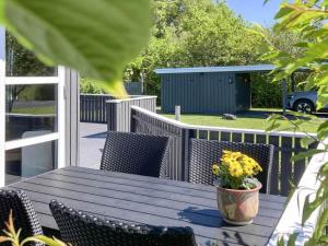 a wooden table with chairs and a vase of flowers on a deck at 4 person holiday home in Vinderup in Vinderup