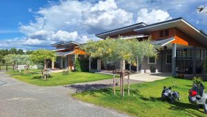 a house with some trees in front of it at บ้านน้ำผึ้งโฮมสเตย์ Pool & Garden in Suan Phung
