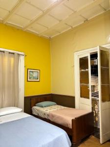 two beds in a room with yellow walls at El Duke Kahanamoku surf hostel in Pacasmayo